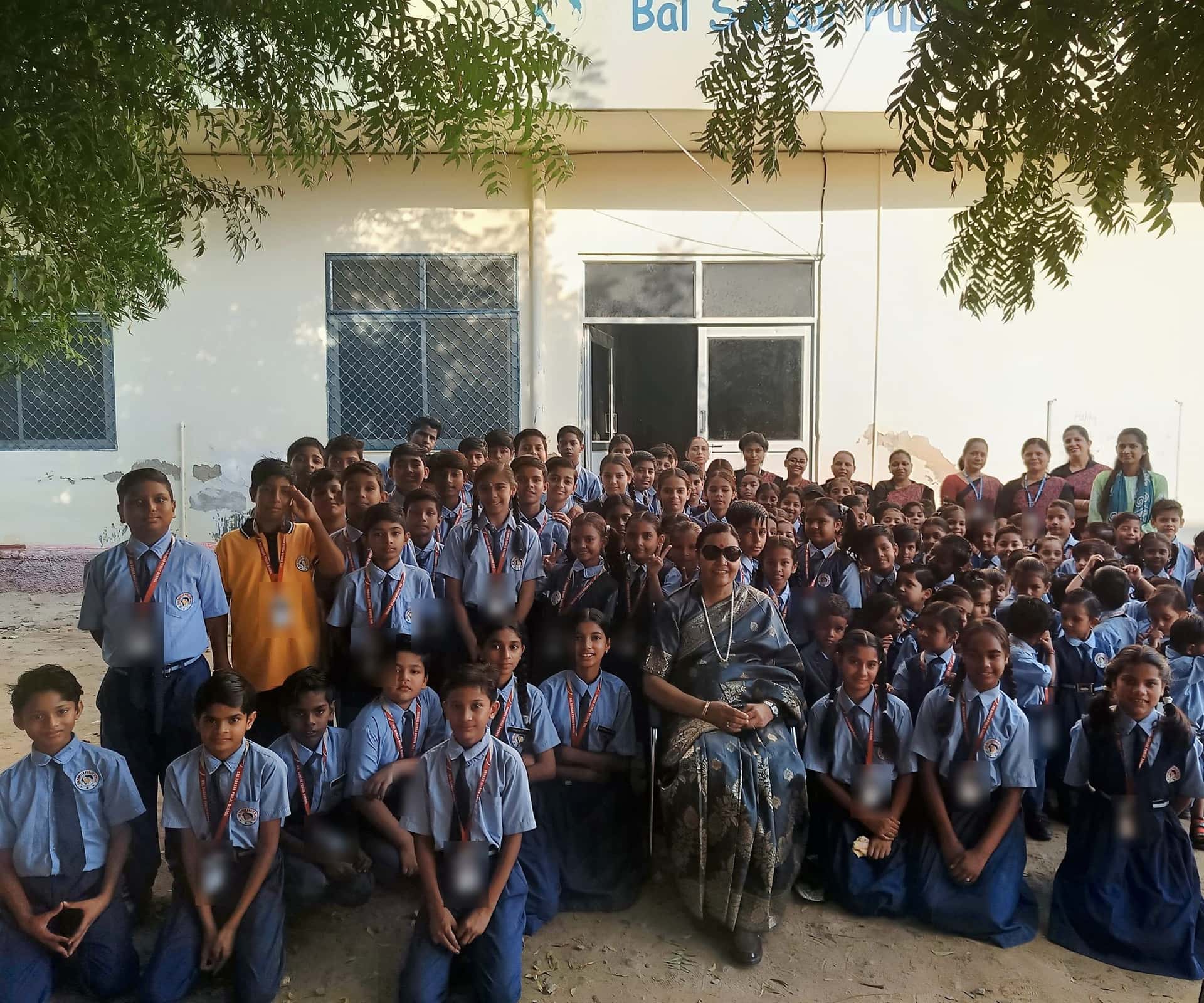 BSPS students and staff gathered outside the school building around a seated guest
