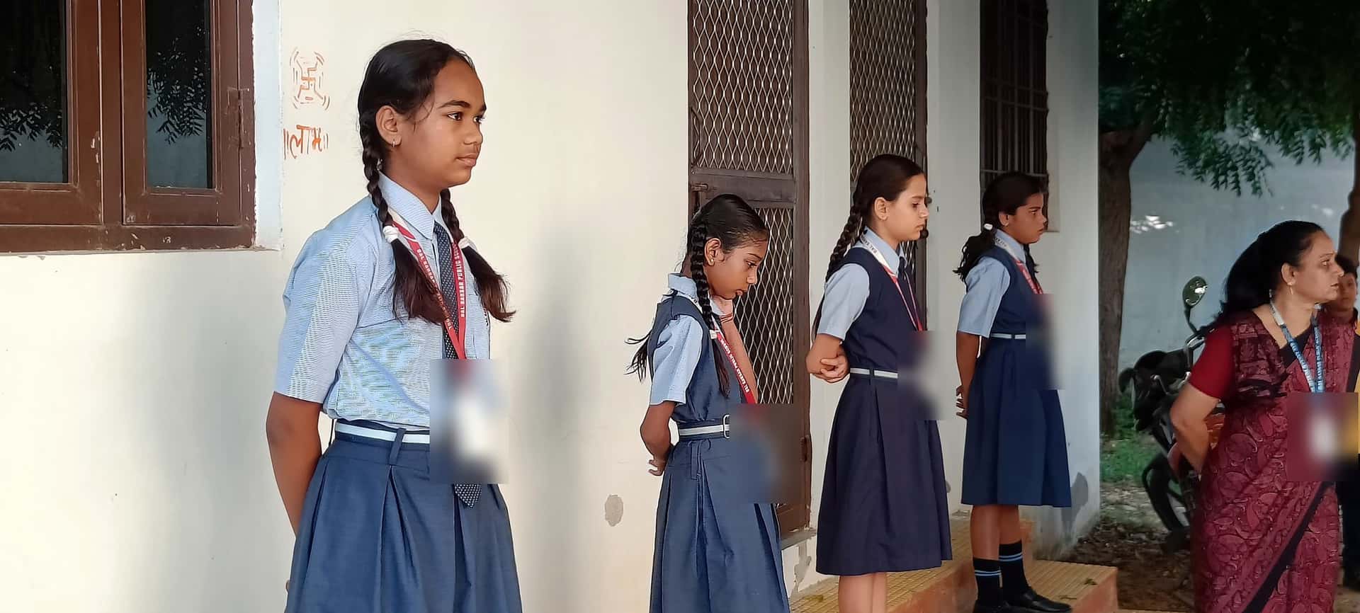 Older BSPS girls stand in a line beside the school building