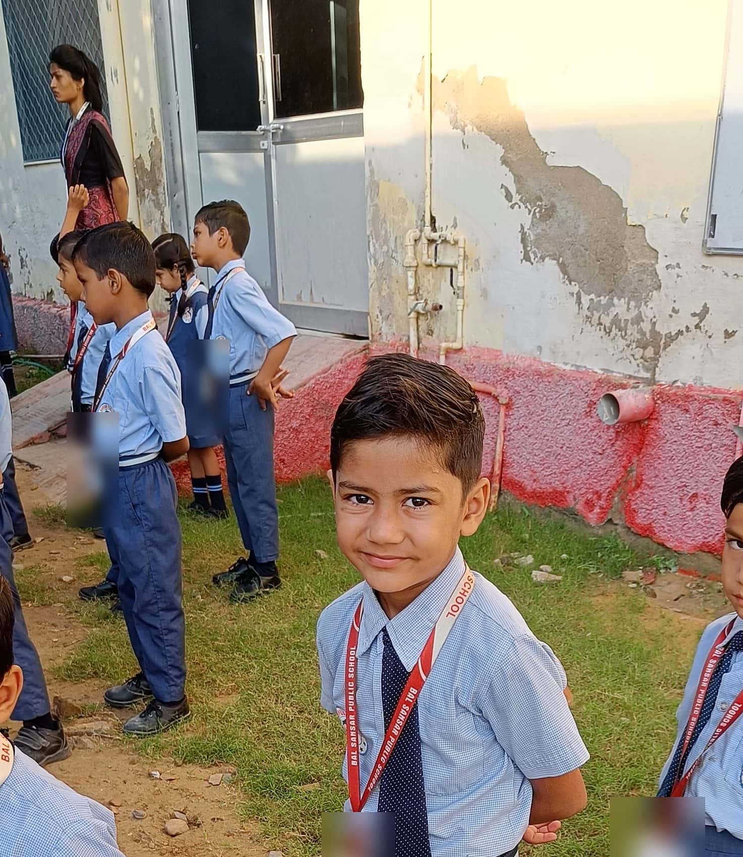 A smiling BSPS pupil in front of his class, lined up in the courtyard