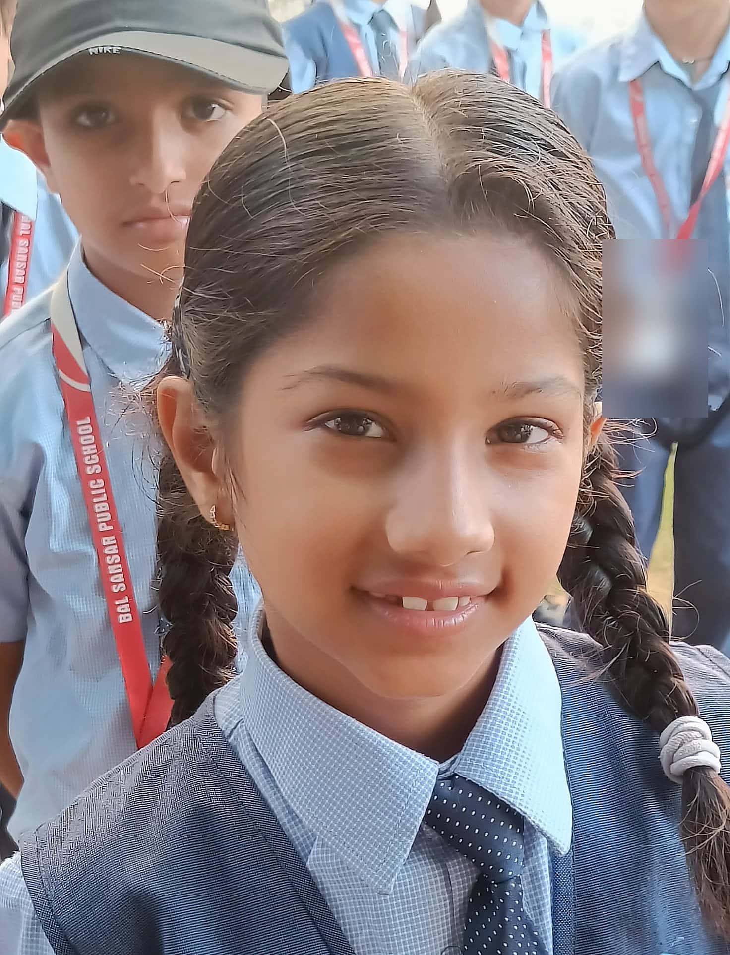 A smiling BSPS pupil with braided hair in her school uniform