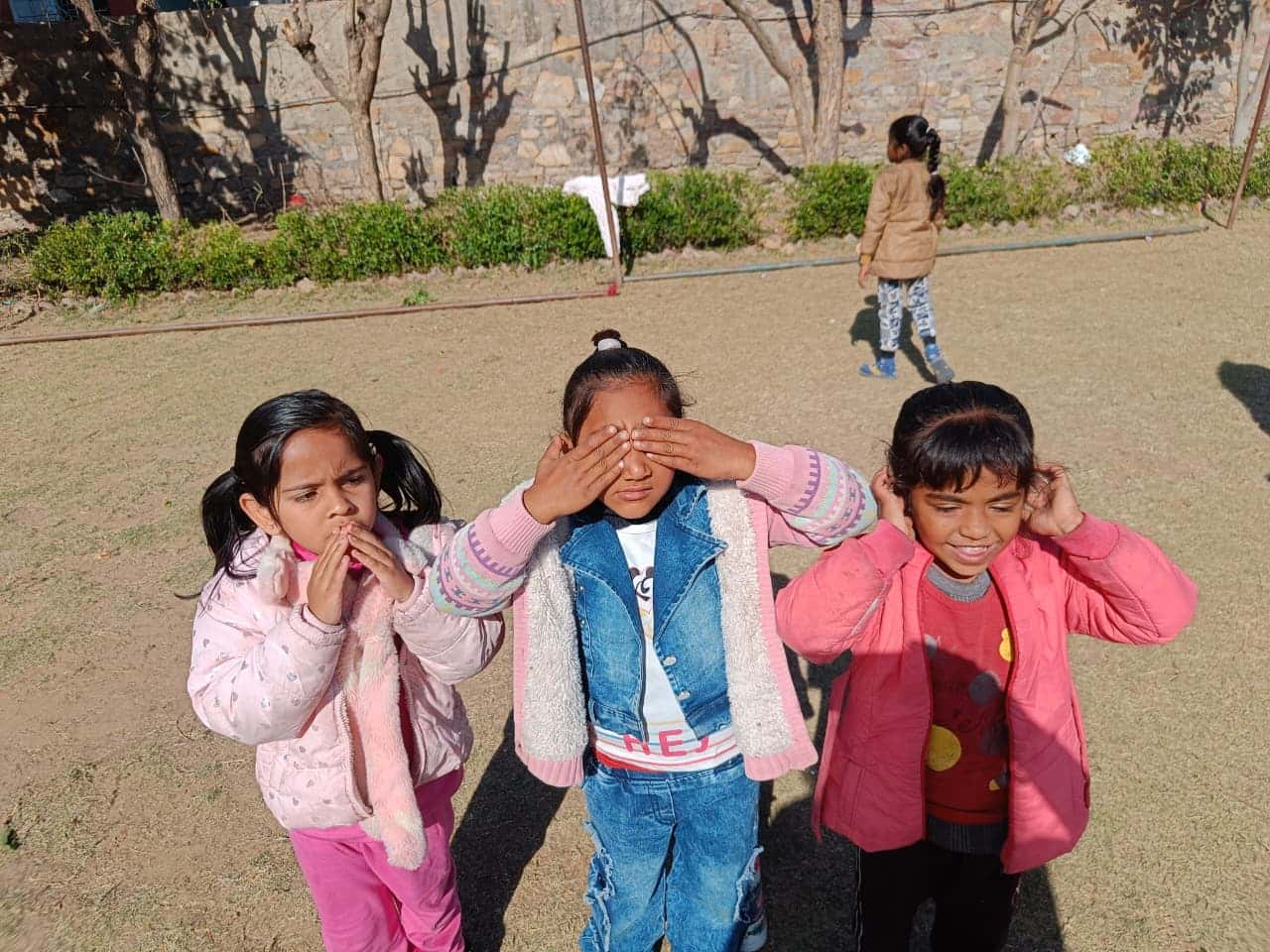 Three children playfully posing as see-no-evil, hear-no-evil, speak-no-evil