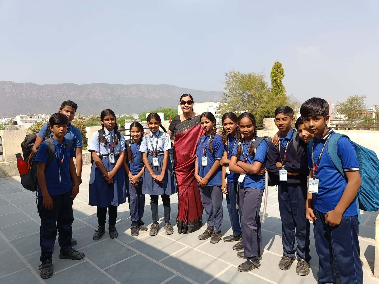 Founder with students on the school rooftop with Aravalli hills