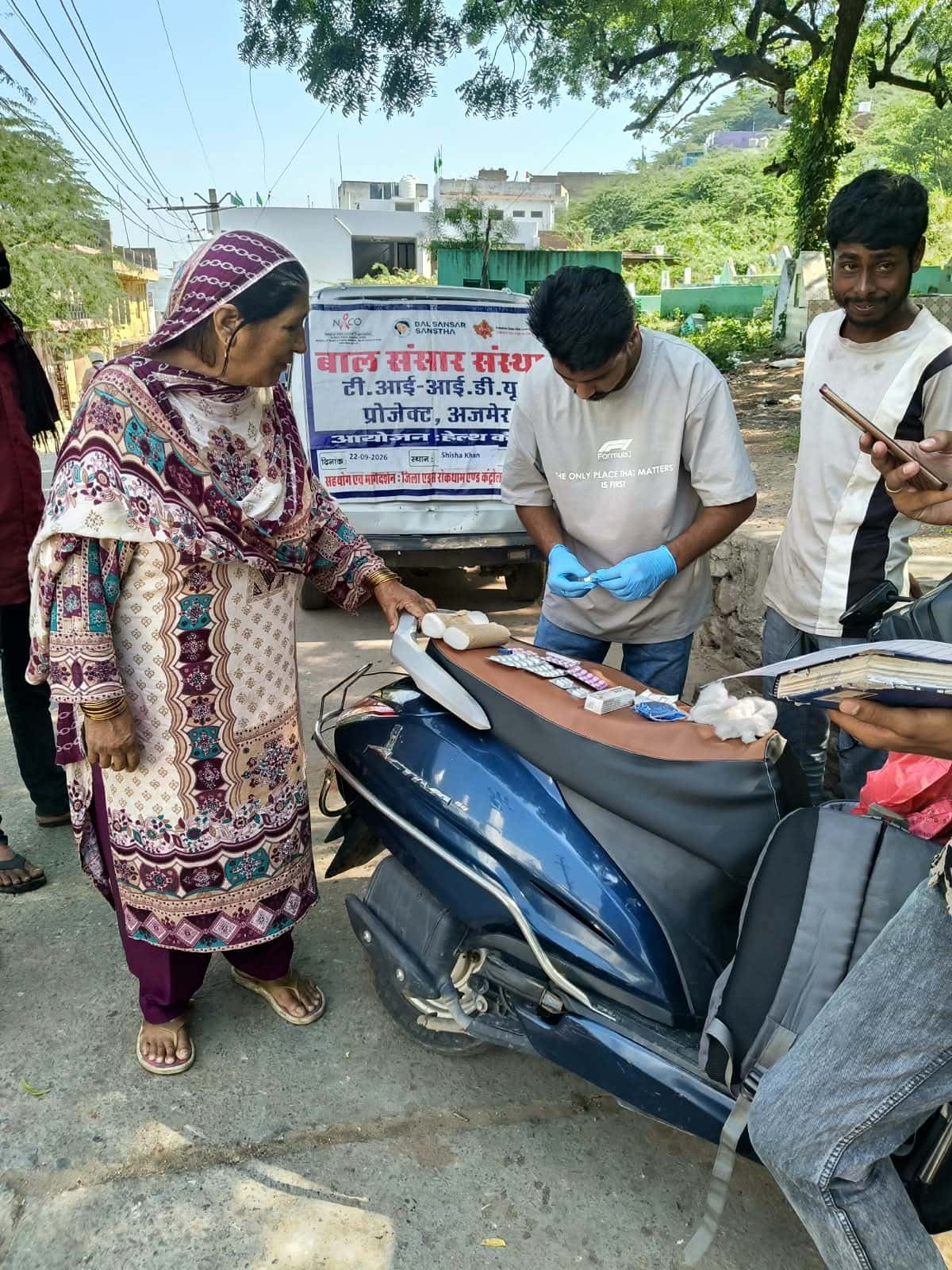 An older woman at the camp, beside the scooter laid out with medicine strips and cotton
